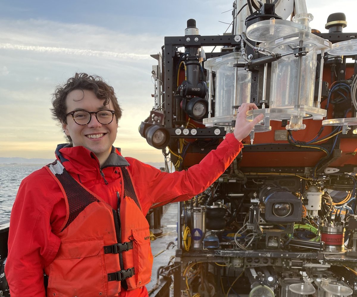 Darrin Schultz on the deck of a research vessel next to an ROV
